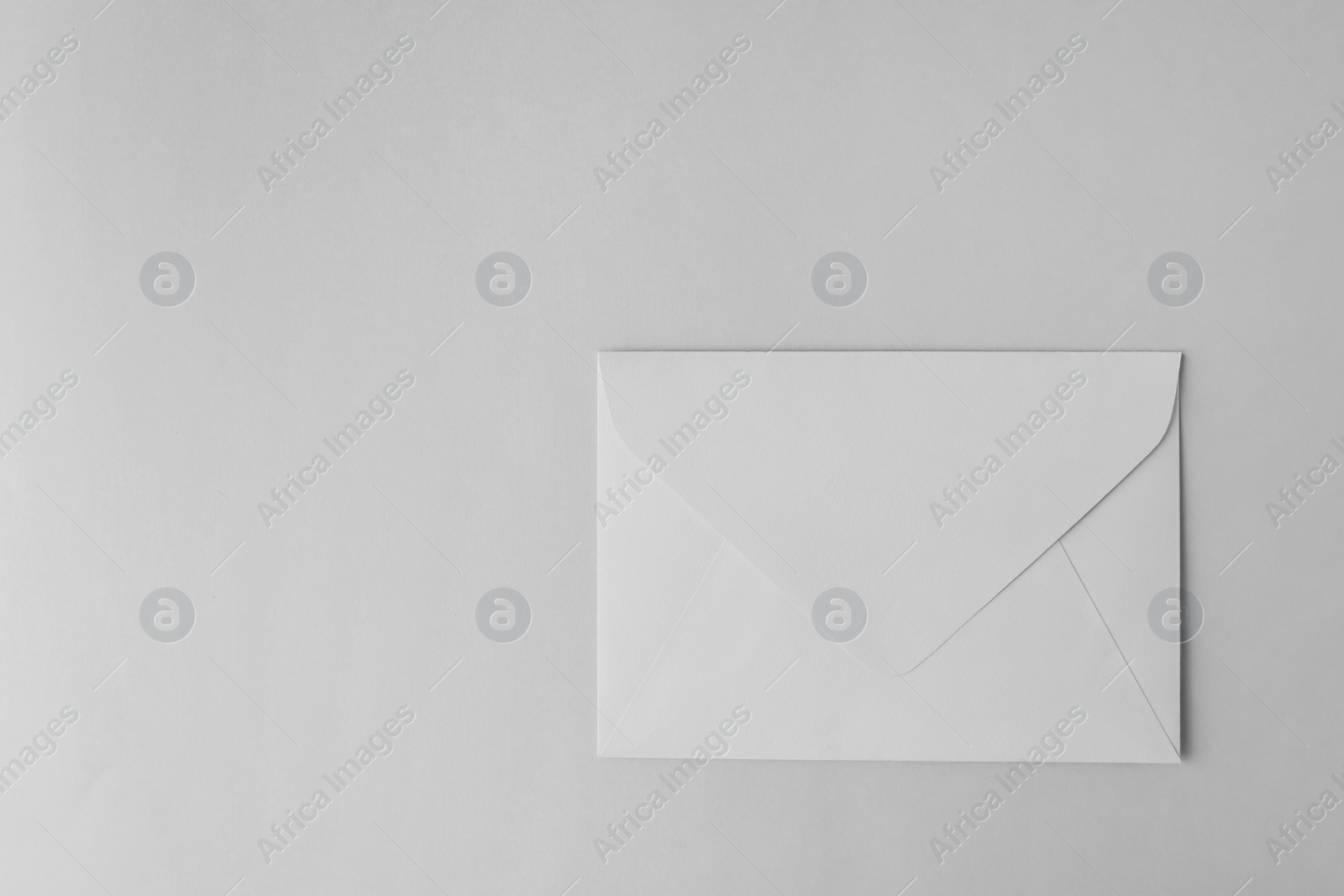 Photo of Paper envelope on light grey background, top view. Space for text