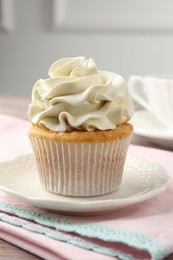 Photo of Tasty cupcake with vanilla cream on pink wooden table, closeup