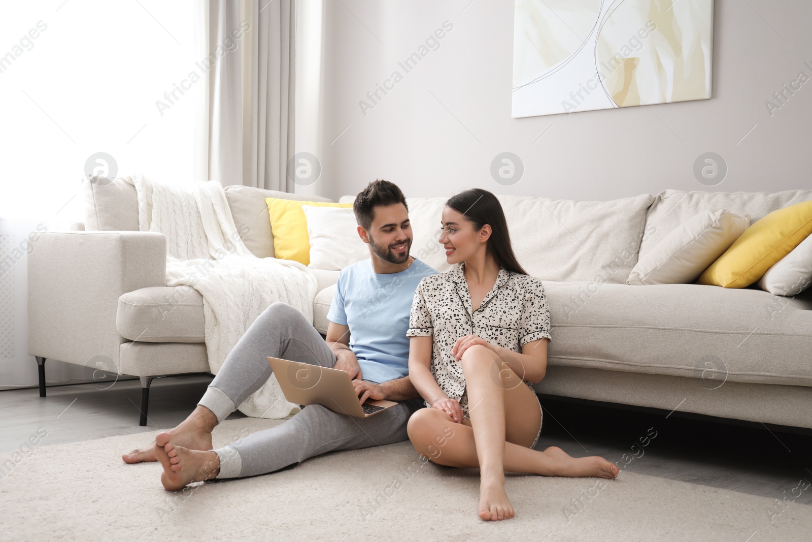 Photo of Happy couple in pajamas with laptop at home