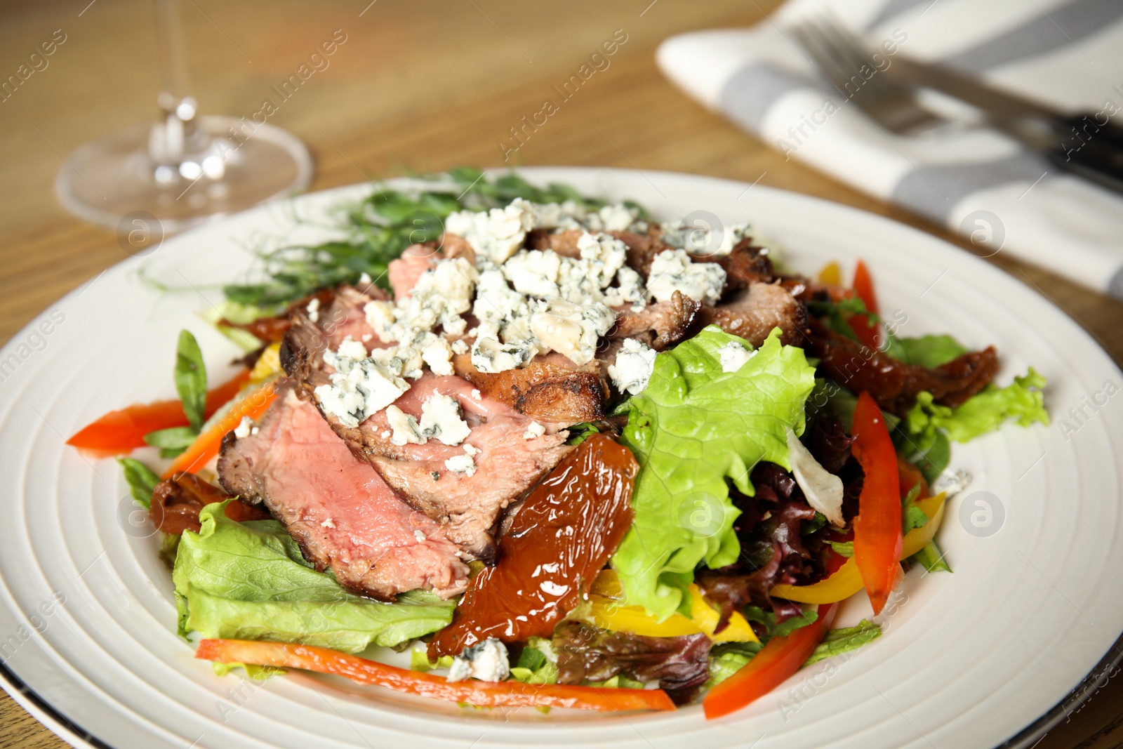 Photo of Delicious salad with roasted meat and vegetables served on table, closeup