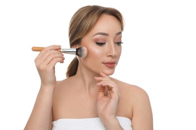 Beautiful young woman applying face powder with brush on white background