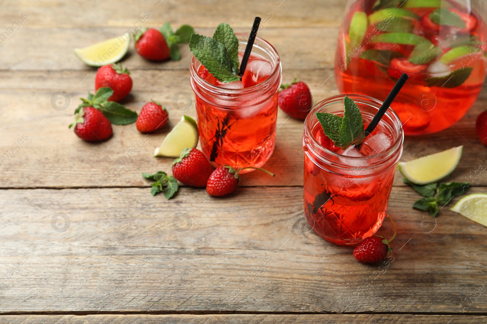 Photo of Refreshing drink with strawberry and lime on wooden table