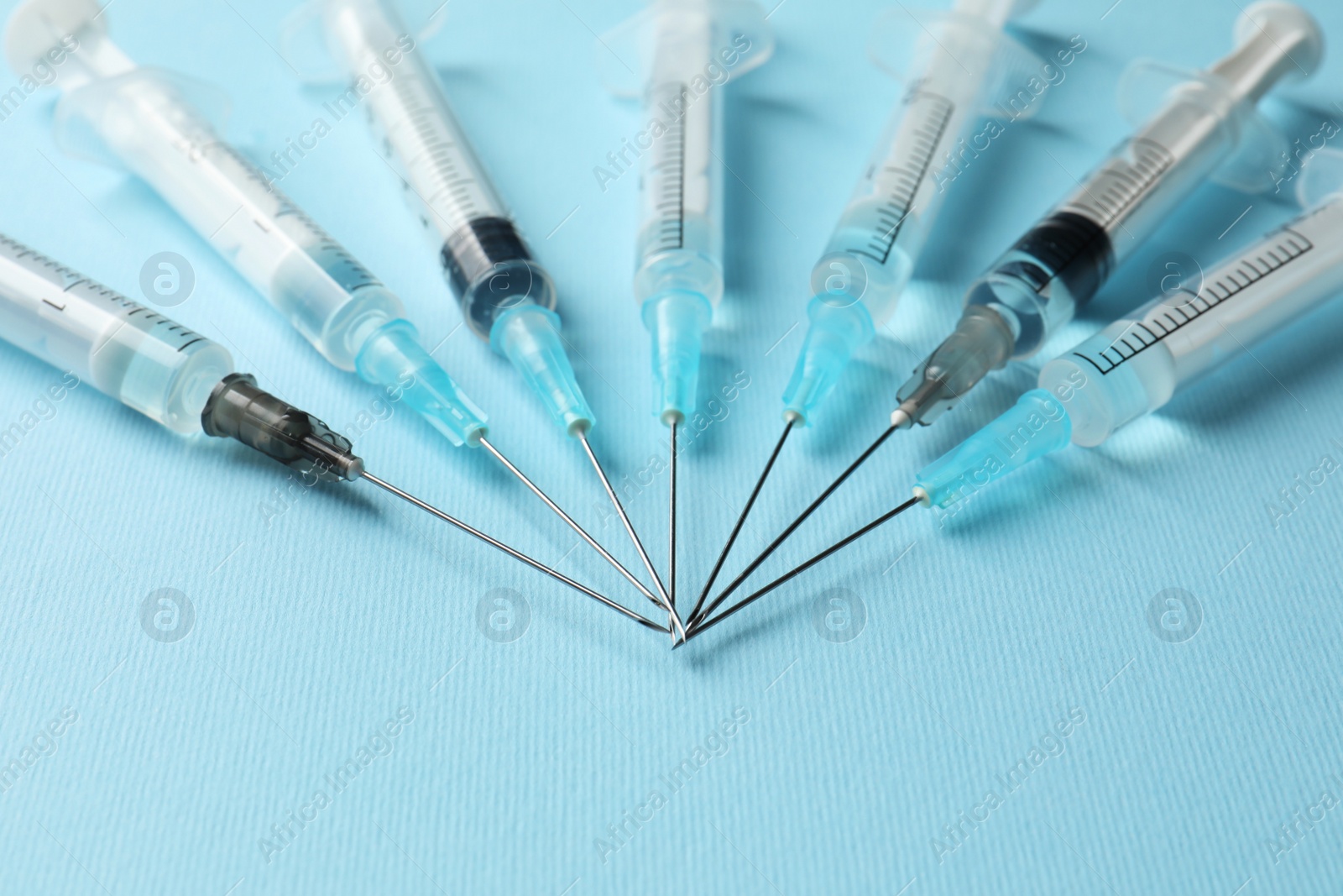 Photo of Disposable syringes with needles and medicine on light blue background