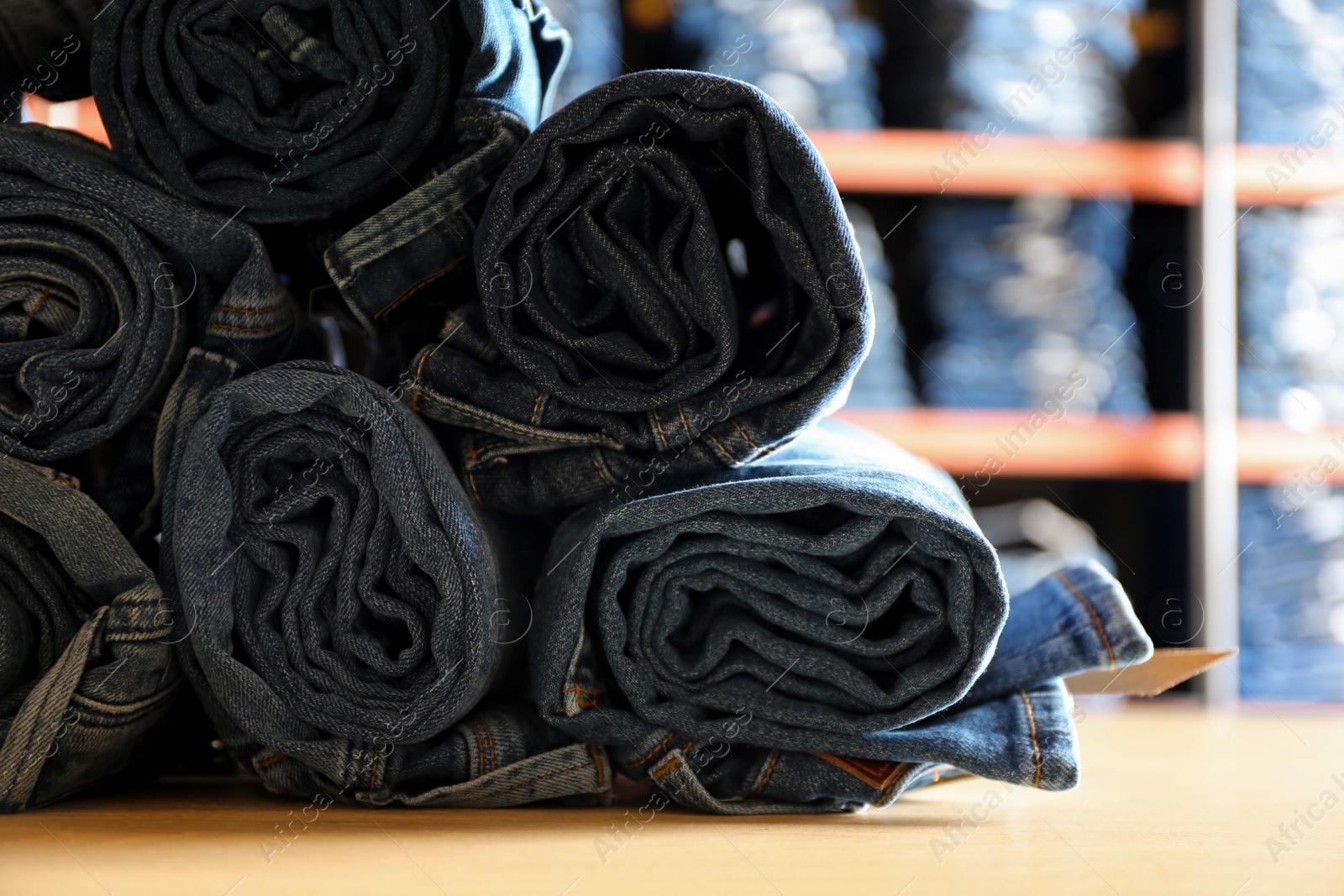 Photo of Rolled modern jeans on display in shop, closeup