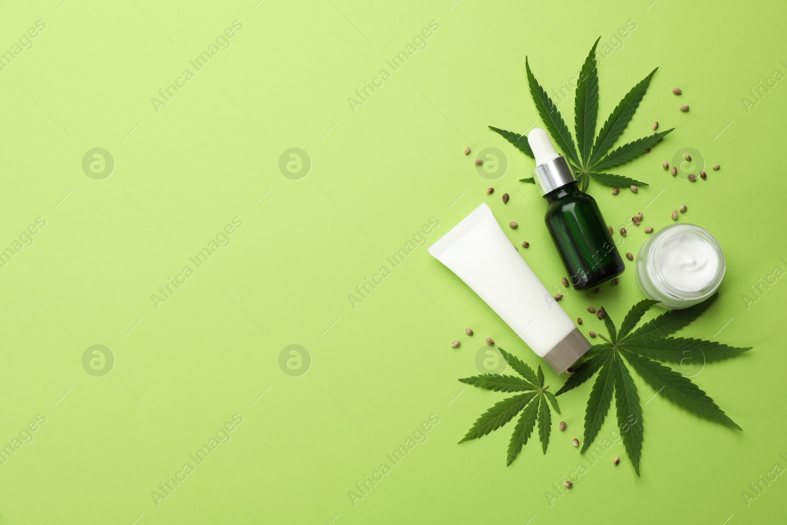 Photo of Flat lay composition with CBD oil or THC tincture and hemp leaves on green background, space for text