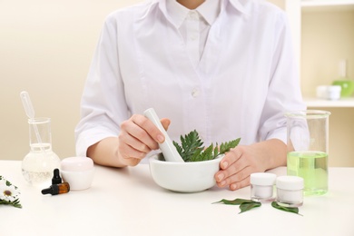 Female dermatologist creating skin care product at table, closeup