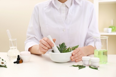 Photo of Female dermatologist creating skin care product at table, closeup