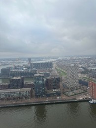 Picturesque view of city with modern buildings and harbor on cloudy day