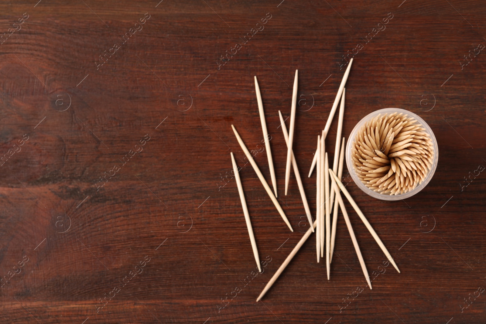 Photo of Disposable toothpicks and holder on wooden background, flat lay. Space for text