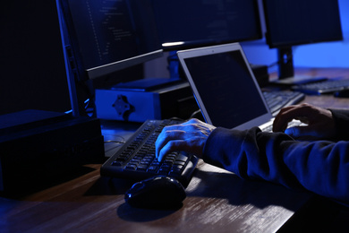Photo of Hacker with computers in dark room, closeup. Cyber crime
