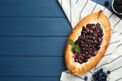Photo of Delicious sweet cottage cheese pastry with cherry jam on blue wooden table, flat lay. Space for text