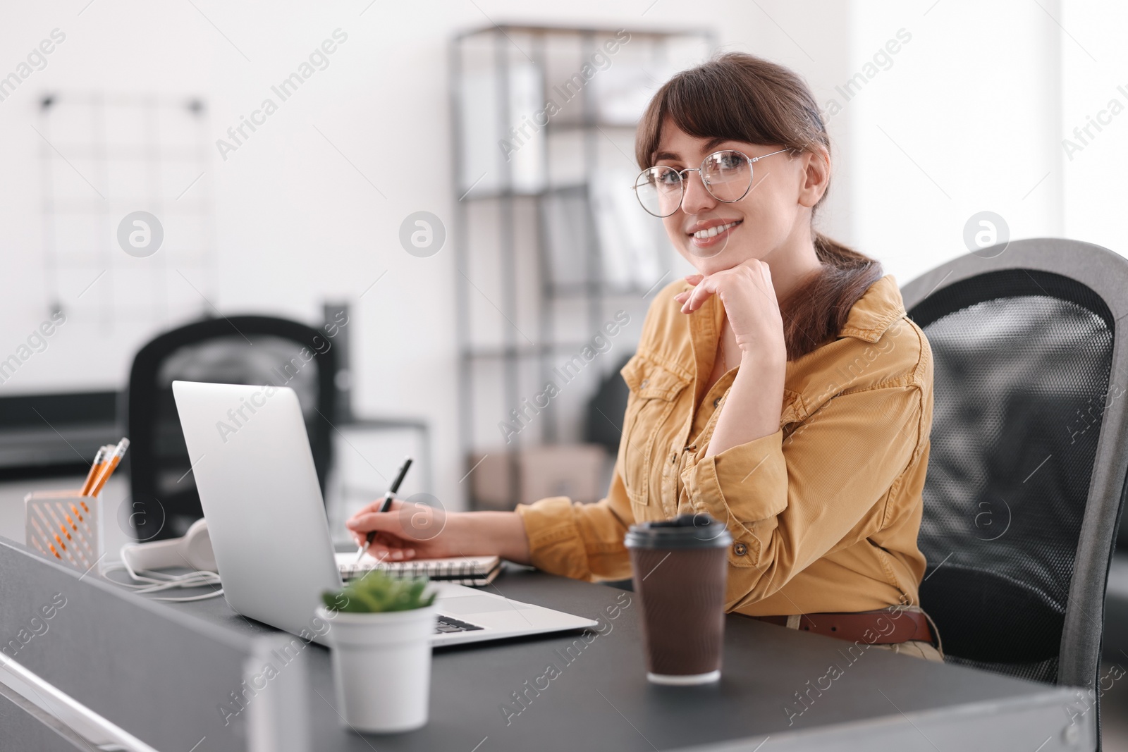 Photo of Woman taking notes during webinar at table indoors