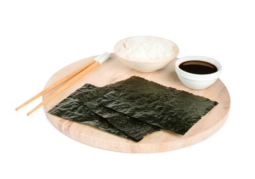 Wooden board with dry nori sheets, rice, soy sauce and chopsticks on white background