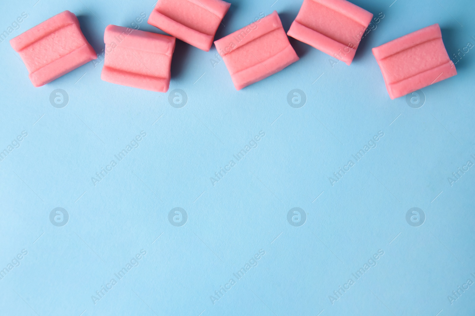 Photo of Tasty chewing gums on light blue background, flat lay. Space for text