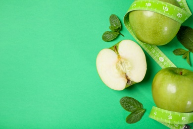 Fresh apples, mint leaves and measuring tape on green background, flat lay. Space for text