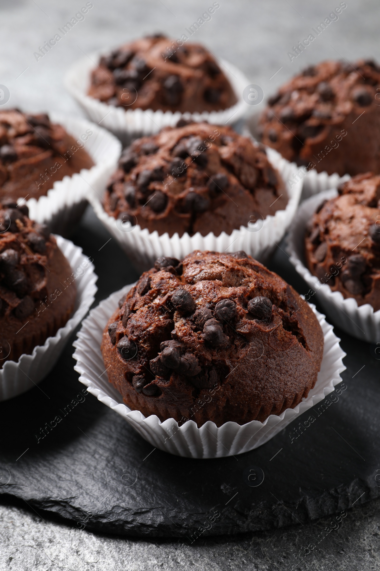 Photo of Tasty chocolate muffins on grey textured table, closeup