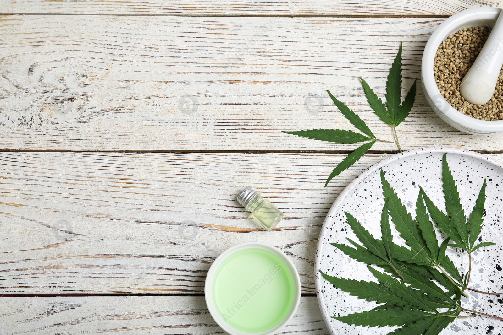 Photo of Flat lay composition with hemp leaves, seeds, cosmetic products and space for text on wooden background