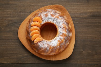 Photo of Homemade yogurt cake with tangerines and powdered sugar on wooden table, top view