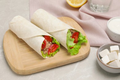 Photo of Delicious tortilla wraps with tuna on light grey table
