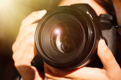 Image of Photographer with professional camera on blurred background, closeup