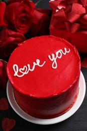 Bento cake with text Love You, roses and gift box on black wooden table. St. Valentine's day surprise