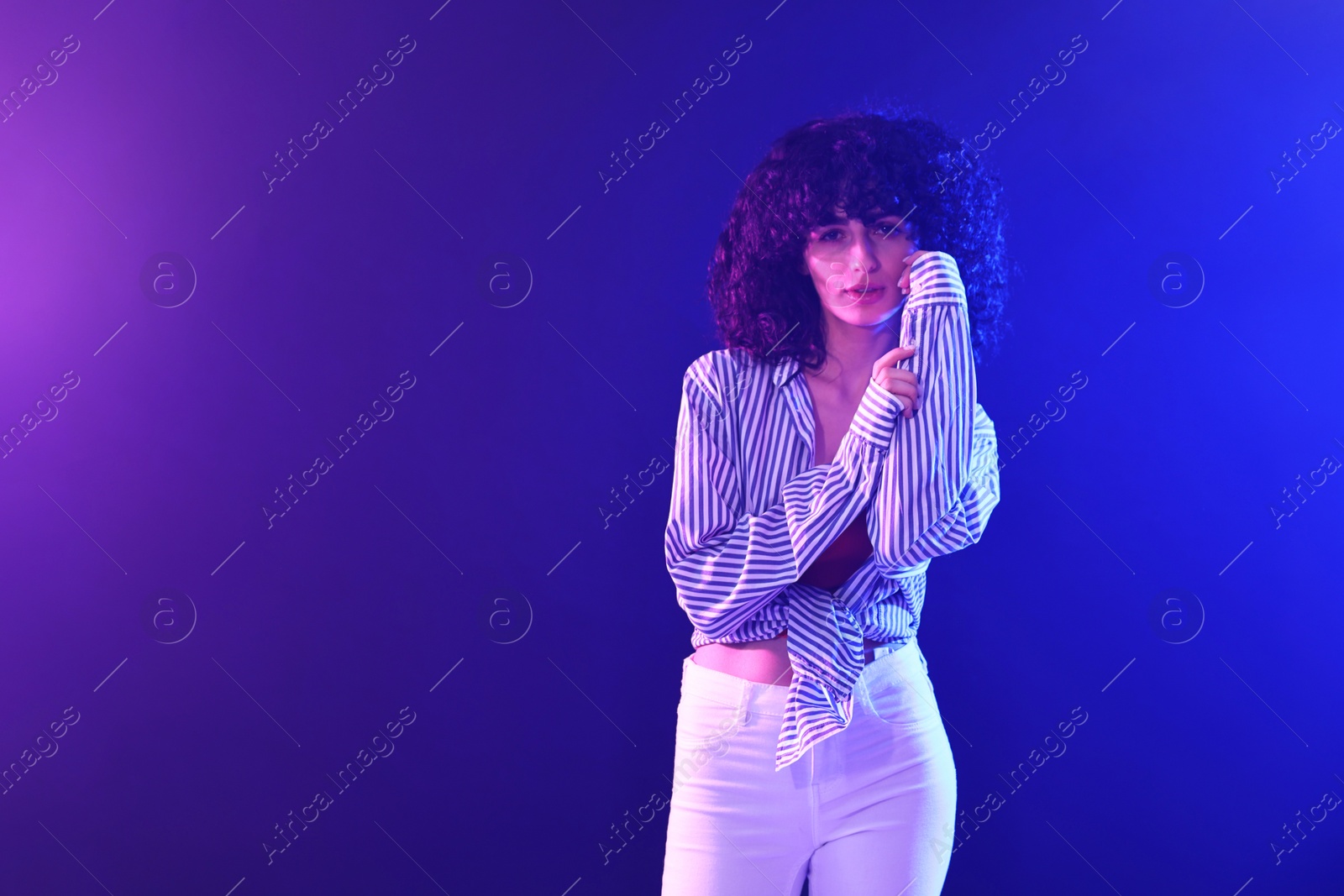 Photo of Beautiful young woman posing on color background in neon lights. Space for text