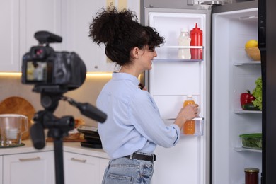 Food blogger recording video near fridge in kitchen