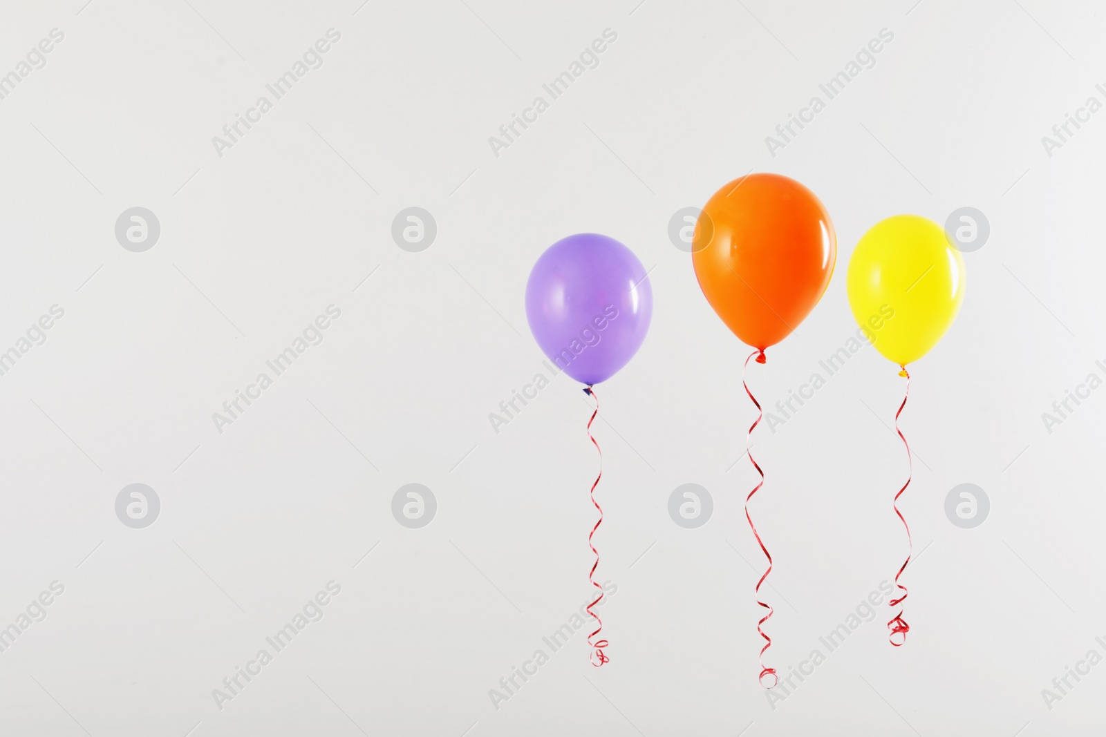 Photo of Different bright balloons on light background, space for text. Celebration time