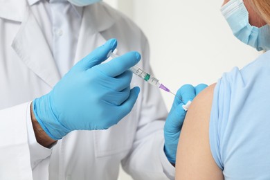 Doctor giving hepatitis vaccine to patient on white background, closeup