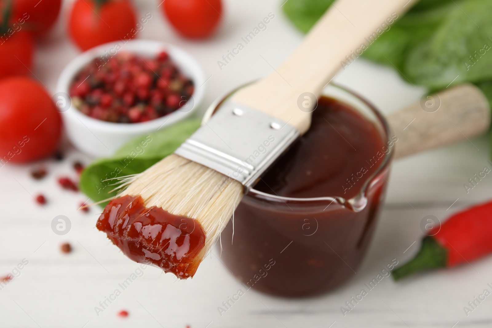Photo of Marinade and basting brush on white table, selective focus