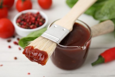Photo of Marinade and basting brush on white table, selective focus