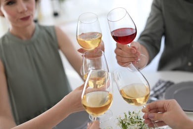 Photo of Young people with glasses of delicious wine indoors