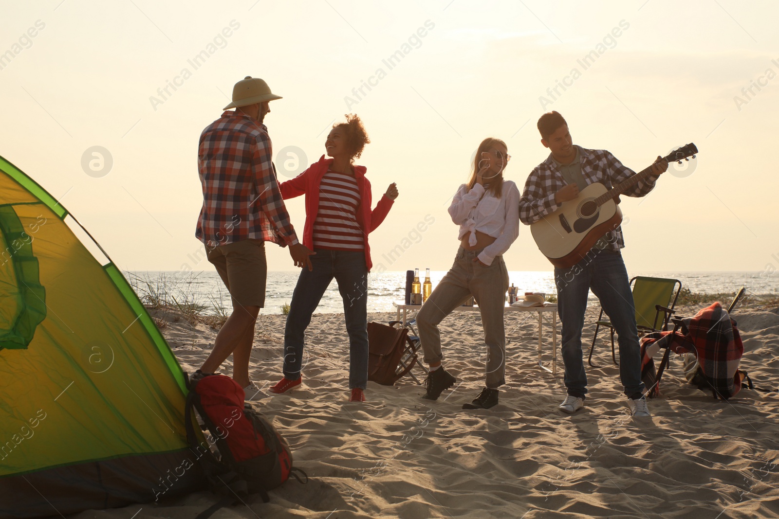 Photo of Friends having party near camping tent on sandy beach