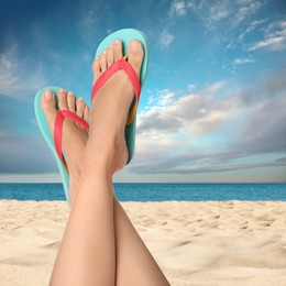 Image of Woman wearing stylish flip flops resting on sandy beach and enjoying beautiful seascape, closeup 