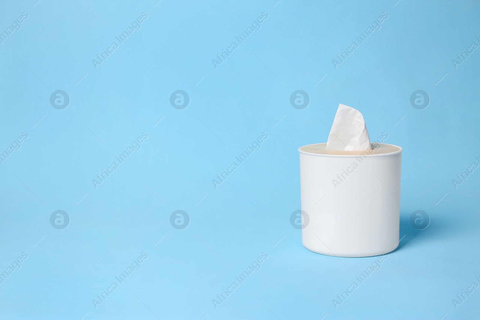 Photo of Holder with paper tissues on light blue background. Space for text