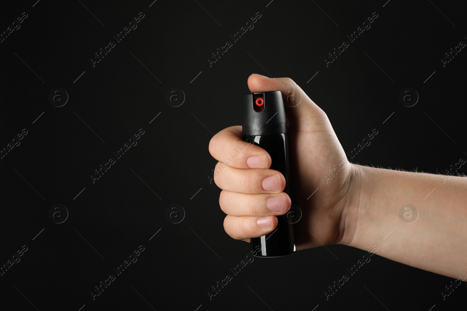 Photo of Man holding pepper spray on black background, closeup. Space for text