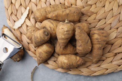 Photo of Tubers of turnip rooted chervil and peeler on gray table, top view