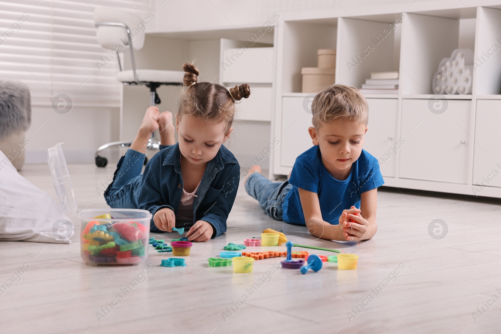 Photo of Cute little children playing on warm floor at home. Heating system