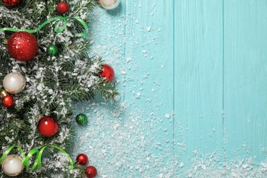 Flat lay composition with fir branches, Christmas decoration and snow on light blue wooden background. Space for text