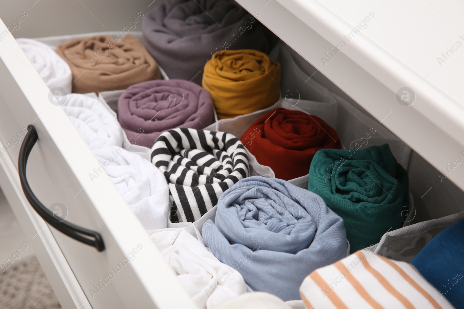 Photo of Open drawer with folded clothes indoors, closeup. Vertical storage