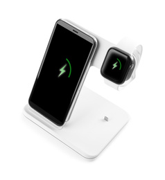 Photo of Mobile phone and smartwatch charging with wireless pad isolated on white
