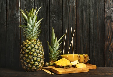 Photo of Fresh pineapples on table against wooden wall