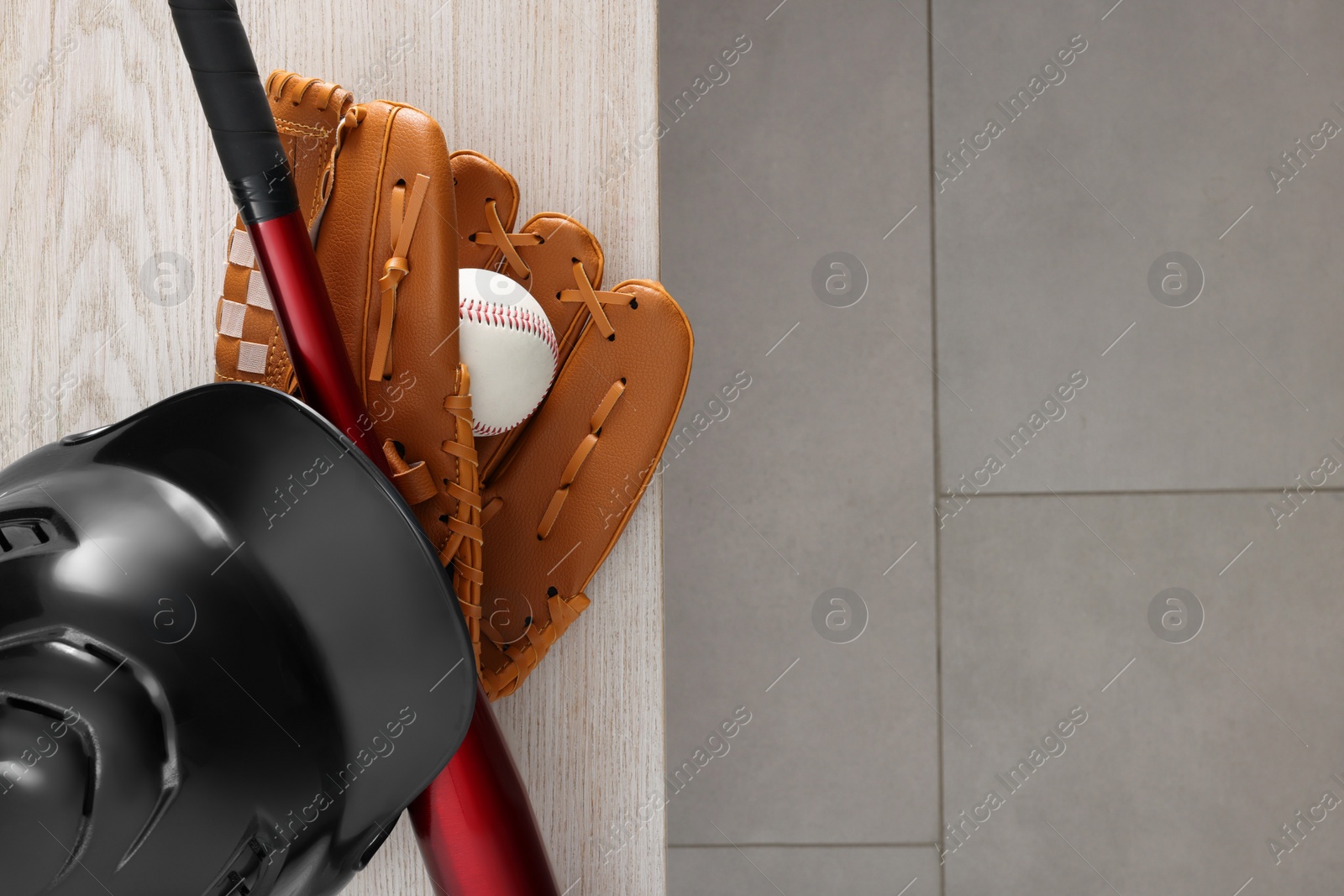 Photo of Baseball bat, batting helmet, leather glove and ball on wooden bench indoors, top view. Space for text