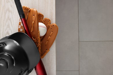 Baseball bat, batting helmet, leather glove and ball on wooden bench indoors, top view. Space for text