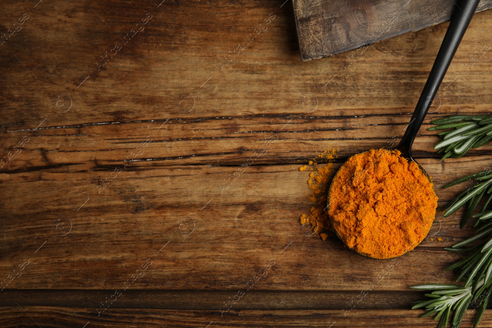 Photo of Spoon with saffron powder and rosemary on wooden table, flat lay. Space for text