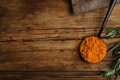 Photo of Spoon with saffron powder and rosemary on wooden table, flat lay. Space for text