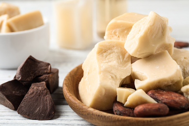 Composition with organic cocoa butter on white wooden table, closeup