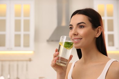 Photo of Young woman with glass of fresh lemonade at home, space for text