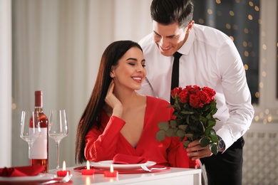 Man presenting roses to his beloved woman in restaurant. Romantic Valentine's day dinner