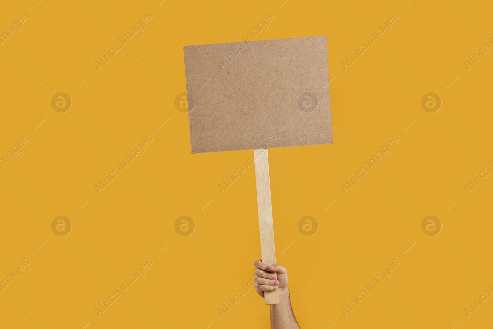 Photo of Man holding blank sign on orange background, closeup. Space for text